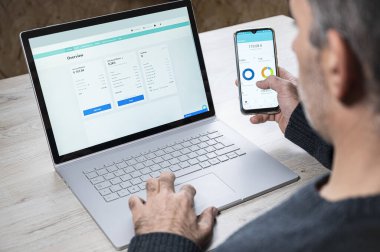 Kafkasyalı bir adam akıllı telefon uygulamasında online bankacılık uygulamasını izliyor.