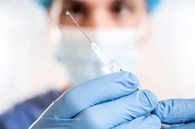 Doktor elinde Coronavirus aşısı olan bir şırınga tutuyor. Covid-19 Aşılama