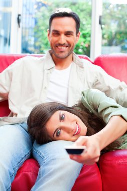 Woman lying on boyfriend's lap while using remote control