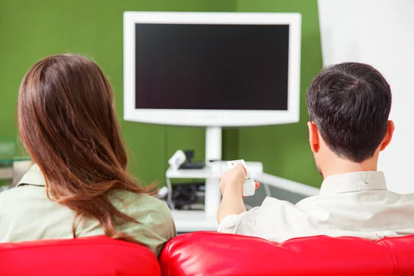 Vue arrière du jeune couple regardant la télévision sur le canapé Images De Stock Libres De Droits