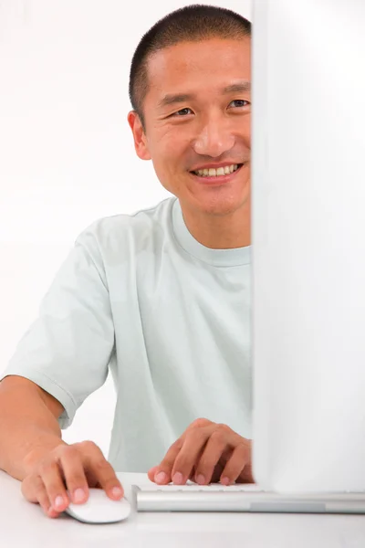 Lachende jonge Aziatische man met behulp van computer — Stockfoto