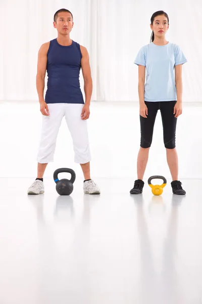 Asian man and woman doing kettle bell crossfit exercise — Stock Photo, Image