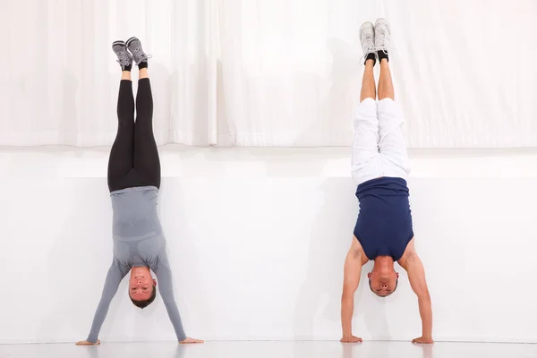 Homme et femme faisant de l'exercice handstand dans la salle de gym — Photo