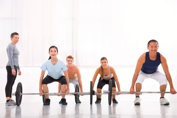 Grupo multiétnico com treinamento de barra de levantamento de peso em cent fitness — Fotografia de Stock