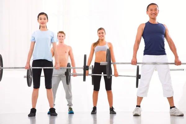 Grupo multiétnico de pessoas que exercem com barra de levantamento de peso em — Fotografia de Stock