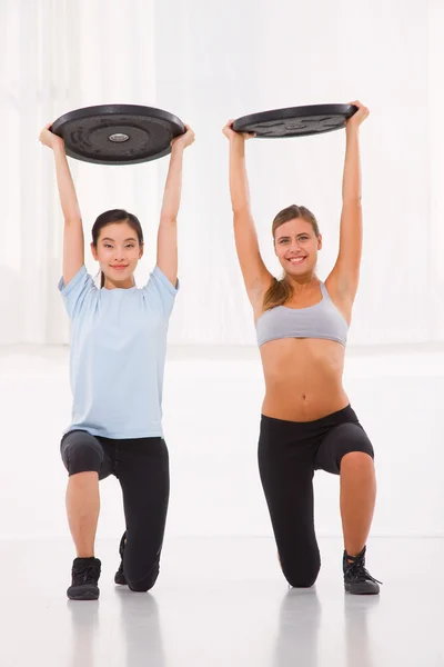 Duas mulheres jovens levantando peso no ginásio — Fotografia de Stock