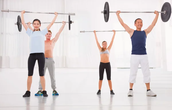 Groupe multiethnique de personnes exerçant avec barre d'haltérophilie à — Photo