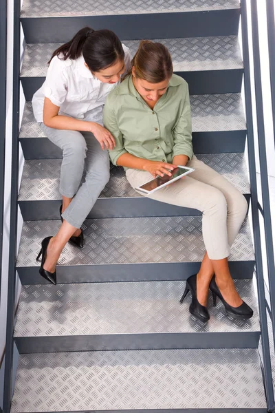 Two women sitting staircase using digital tablet — Stock Photo, Image