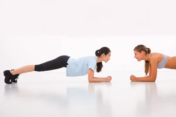 Due giovani donne felici che fanno flessioni in palestra Fotografia Stock