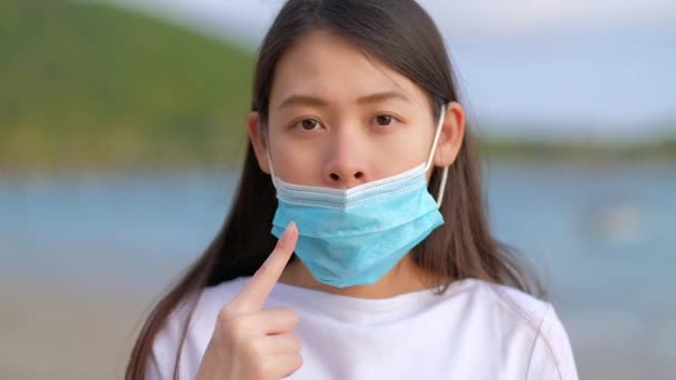 アジアの女性は 顔に保護面を正しく置く方法を示しています 医療用フェイスマスクの使い方が間違っています — ストック動画