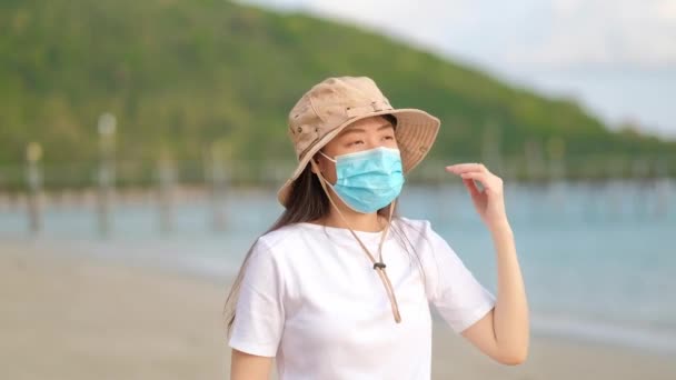 アジアの女性旅行者保護顔マスクビーチを歩くと — ストック動画