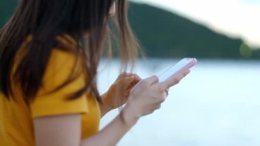 Tropik plajlarda sosyal ağ için akıllı telefonları kullanan bir kadın..