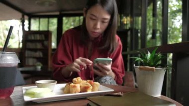 Kahve dükkanında kahvaltı yapan genç bir kadın..