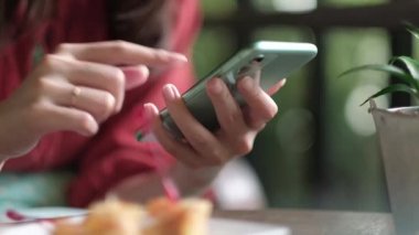 Kahvaltı yaparken elinde akıllı telefon tutan bir kadın..