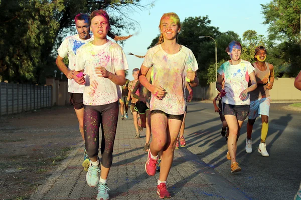 Corriendo grupo de adolescentes y el hombre cubierto con pintura en polvo — Foto de Stock