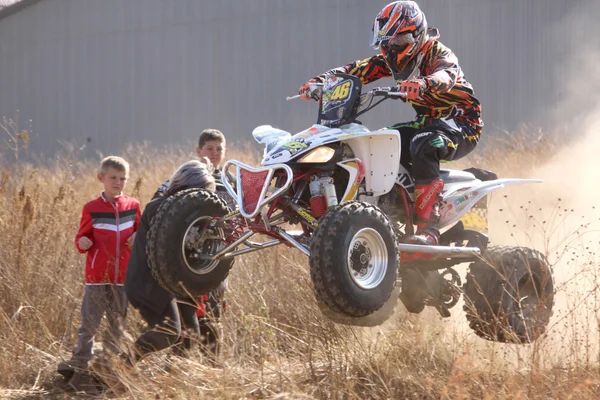 Quad Bike airborne over hump in trail of dust on sand track duri — Zdjęcie stockowe