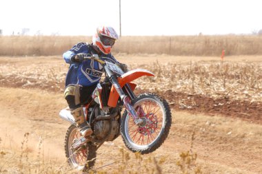 Motorbike wheelie on back wheel kicking up trail of dust on sand