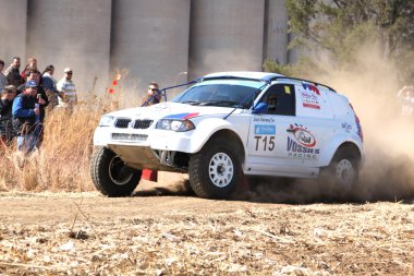 Sürüklenen beyaz Bmw ralli araba dönüşte toz tekme. 