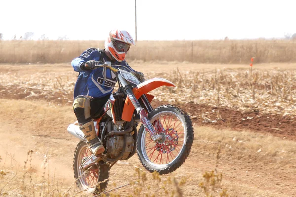 Motorbike wheelie on back wheel kicking up trail of dust on sand — ストック写真