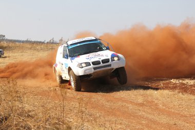 Sürüklenen beyaz Bmw ralli araba dönüşte toz tekme. 