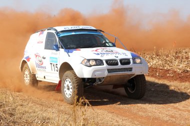 Sürüklenen beyaz Bmw ralli araba dönüşte toz tekme. 