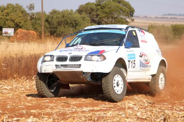 Sürüklenen beyaz Bmw ralli araba dönüşte toz tekme. 