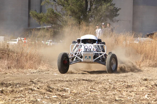 Custom single seater rally buggy kicking up trail of dust on san — Stock Photo, Image