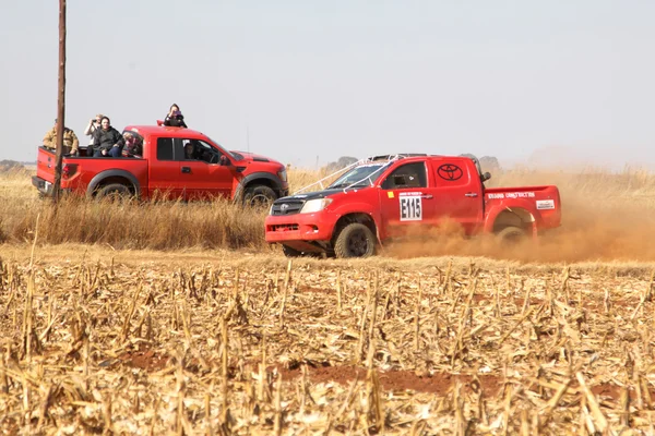 Красный раллийный грузовик Toyota проезжает мимо красного грузовика на пыльной дороге — стоковое фото