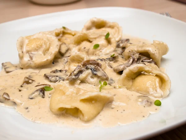 Kaas Tortellini met champignonsaus Stockfoto