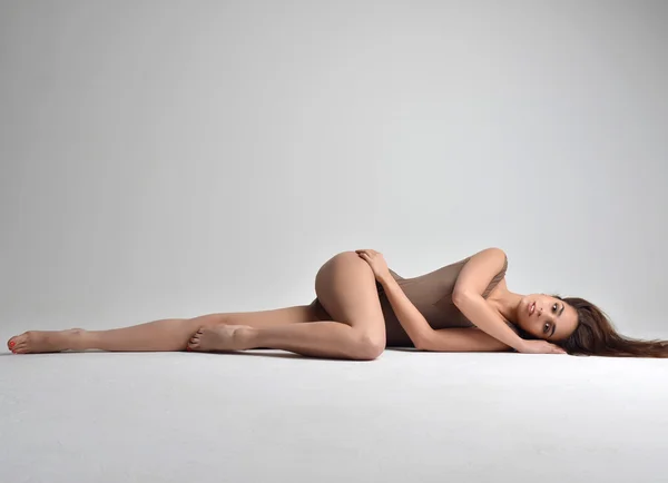 Slanke mooie vrouw liggend op een vloer in sexy ondergoed op grijs — Stockfoto