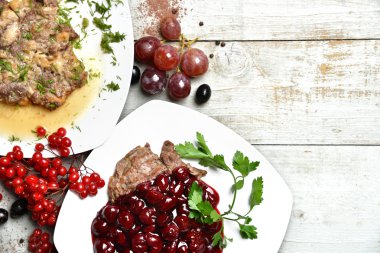 Kiraz ve üzüm ile süslenmiş lezzetli sığır eti ve domuz eti et yemekleri