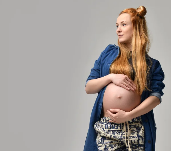 Junge hübsche rote Haare schwangere Bump Frau steht auf einem grauen Bac — Stockfoto