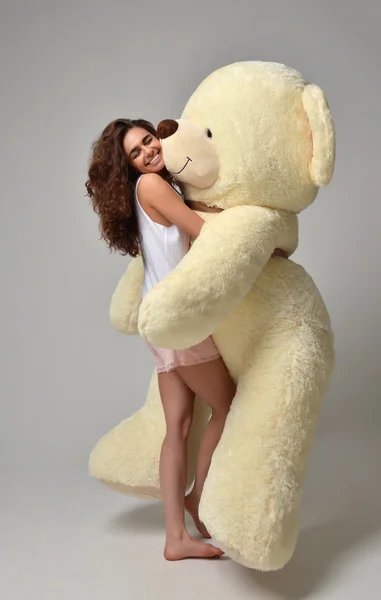 Молода красива дівчина обіймає великого плюшевого ведмедя м'яка іграшка щаслива усмішка — стокове фото