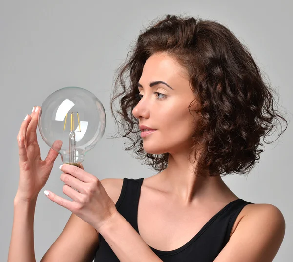 Junge Frau mit lockigem Haar mit neuen großen e27 LED-Glühbirne — Stockfoto