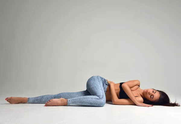 Slim όμορφη μελαχρινή γυναίκα που βρίσκεται σε ένα πάτωμα σε σέξι εσώρουχα — Φωτογραφία Αρχείου