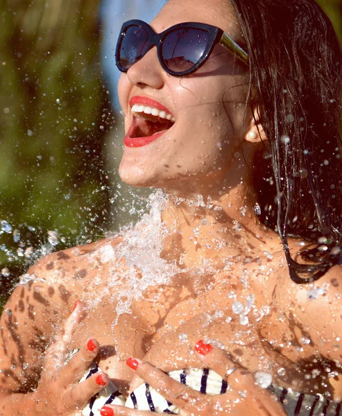 Mooie jongedame met water spatten in zonnebrillen en biki — Stockfoto