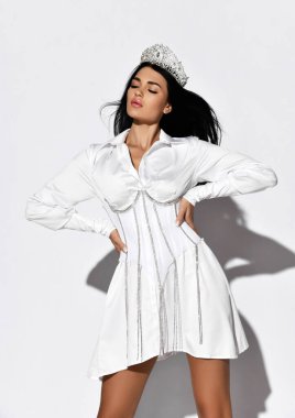 Taçlı ve beyaz korseli elbiseli muhteşem kadın el ele tutuşmuş, başı dönük ve gözleri kapalı duruyor.