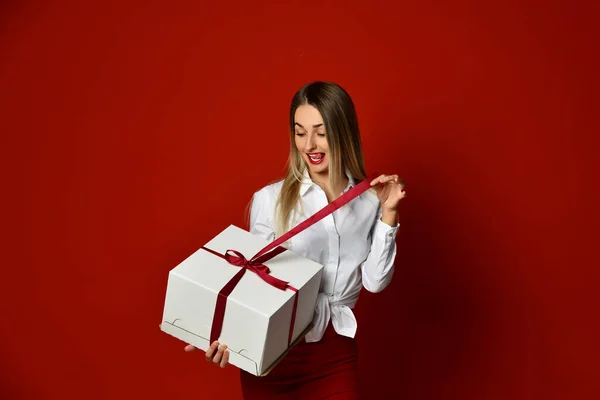 Eccitato felice urlando donna bionda in camicetta bianca disfa confezione regalo grande per Natale e Capodanno 2021 — Foto Stock