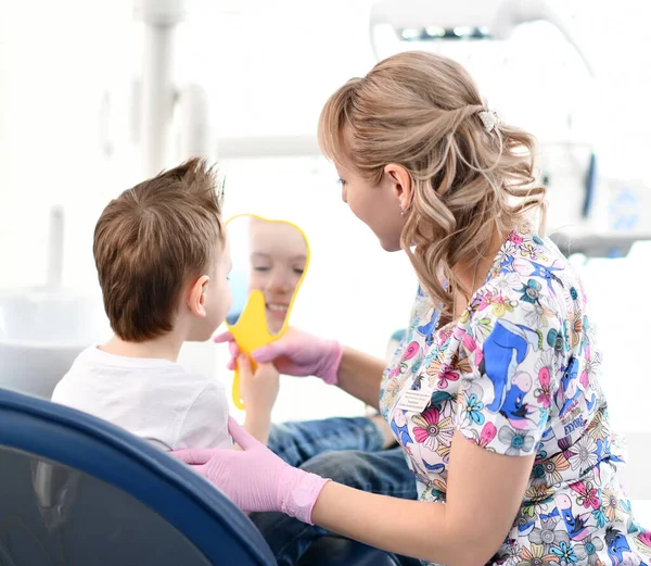 Москва (Росія) - 18 березня 2019: Хлопчик за стоматологічною перевіркою дивиться на свої здорові зуби в дзеркало, яке його стоматолог — стокове фото