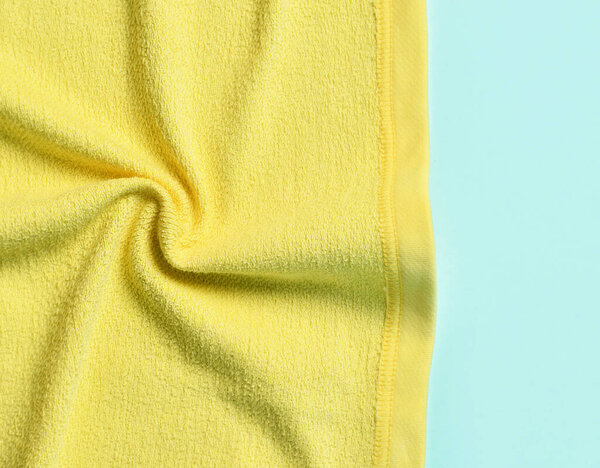 Closeup on yellow slightly twisted fabric, cloth, textile over blue background. Isolated