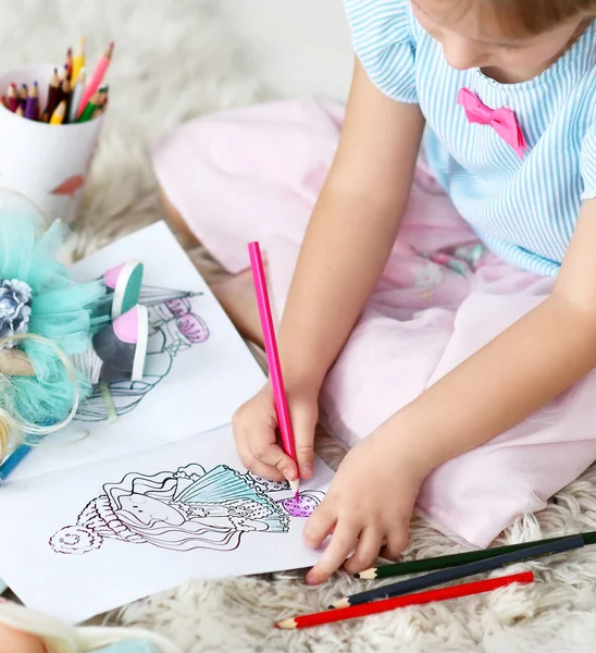 Mãos de menina pequena em casa roupas sentadas no tapete macio e desenho boneca coloração com lápis coloridos em casa — Fotografia de Stock