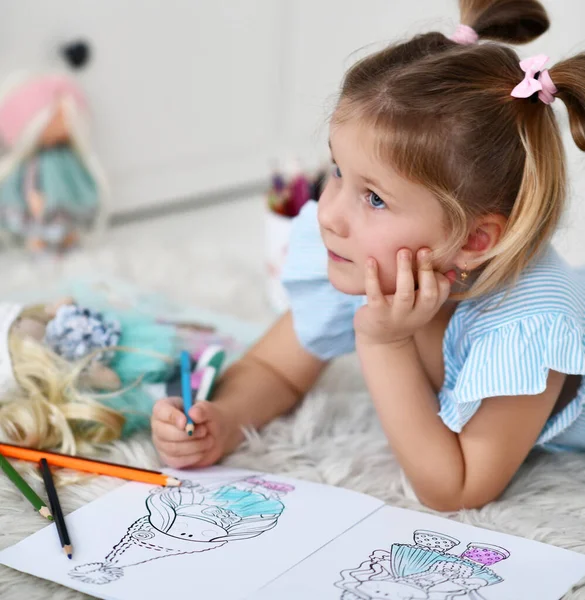 Bonito menina muito pequena em casa roupas sonhando e colorir boneca desenho com lápis coloridos — Fotografia de Stock