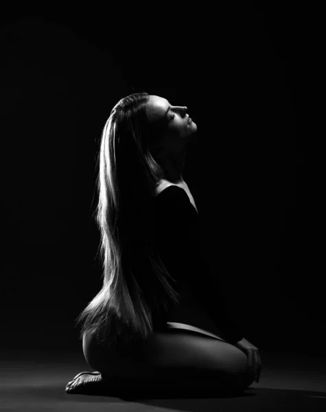 Mujer hermosa joven con el pelo largo y sedoso en el cuerpo oscuro sentado de lado en el suelo con los ojos cerrados —  Fotos de Stock