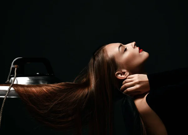 Retrato de una hermosa mujer hermosa posando con los ojos cerrados y su cabello largo y sedoso bajo el hierro a bordo —  Fotos de Stock