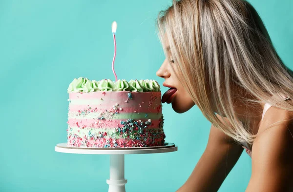 Porträt einer jungen sexy blonden Frau, die auf allen Vieren steht und großen Kuchen mit Sahne und Kerze leckt. Seitenansicht — Stockfoto