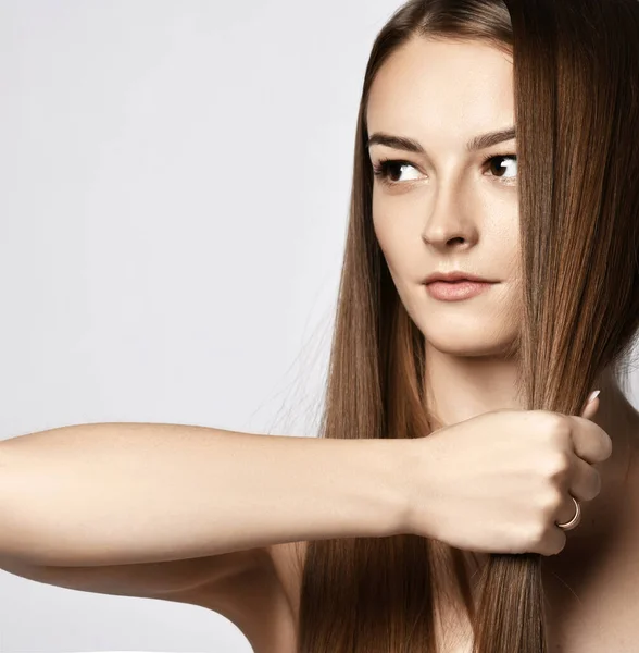 性感的年轻女子的画像，她的手拿着一缕长长的丝状头发，显示出她的力量和健康 — 图库照片