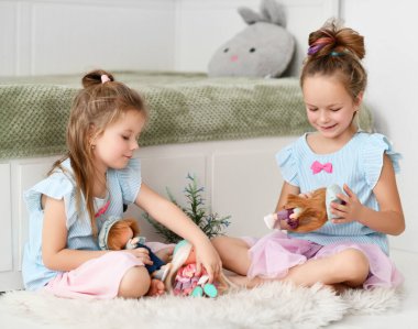 Huzurlu sakin kız kardeşler evde oturup bebekleriyle konuşarak ve oynayarak vakit geçiriyorlar.