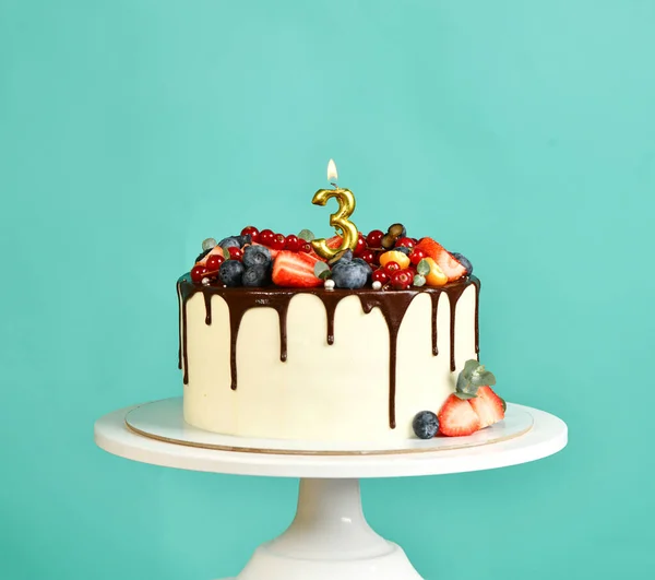 Gâteau sucré de fête d'anniversaire de trois ans avec gouttes de chocolat et fruits frais et 3 bougies allumées — Photo