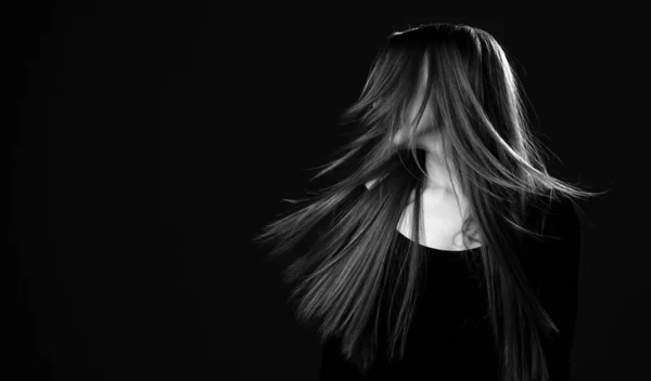 Чорно-білий портрет молодої щасливої жінки зі здоровим відновленим довгим волоссям, що тремтить головою, щоб змусити волосся літати — стокове фото
