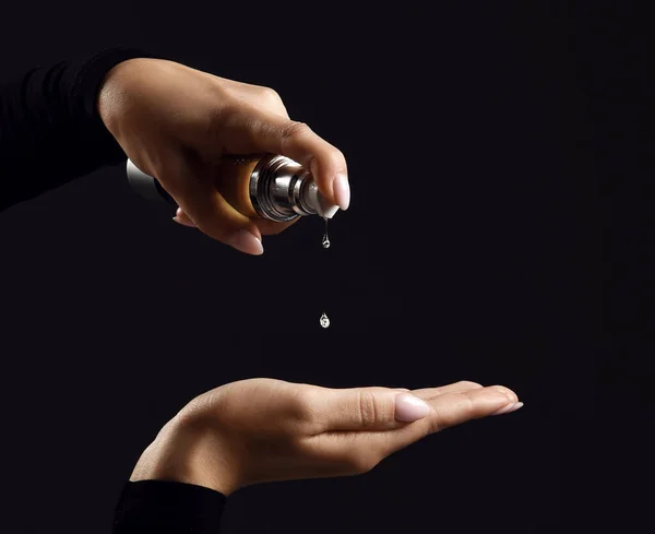 Handen van de vrouw gieten bevochtigende olie voor haarrehabilitatie of behandeling van fles tot hand — Stockfoto